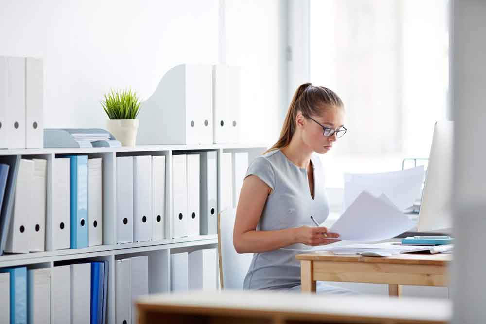 Young accountant looking through papers at workplace